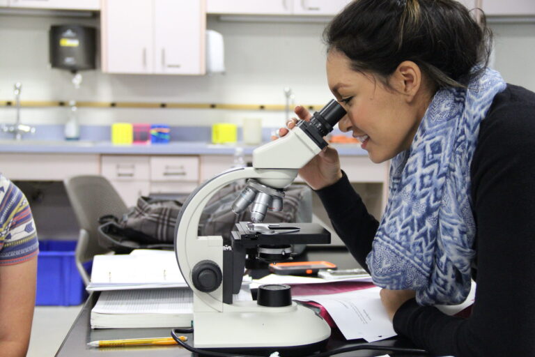 Happy student looking into microscope