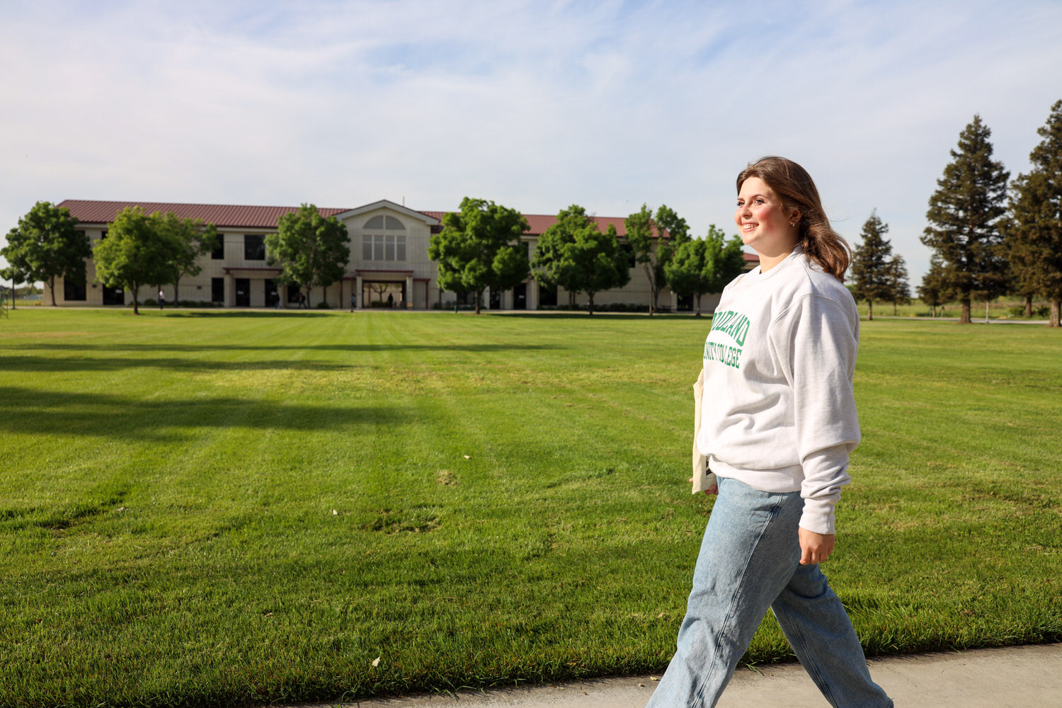 Happy student walking next to green campus space