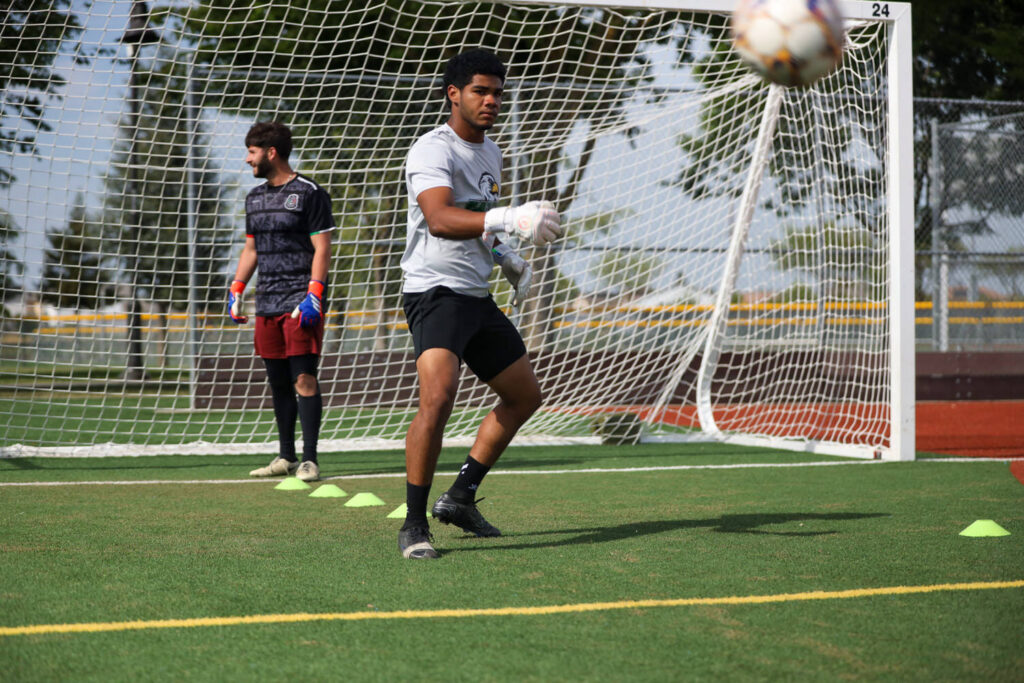 Players from WCC Men's Soccer team in front of goalie during field practice