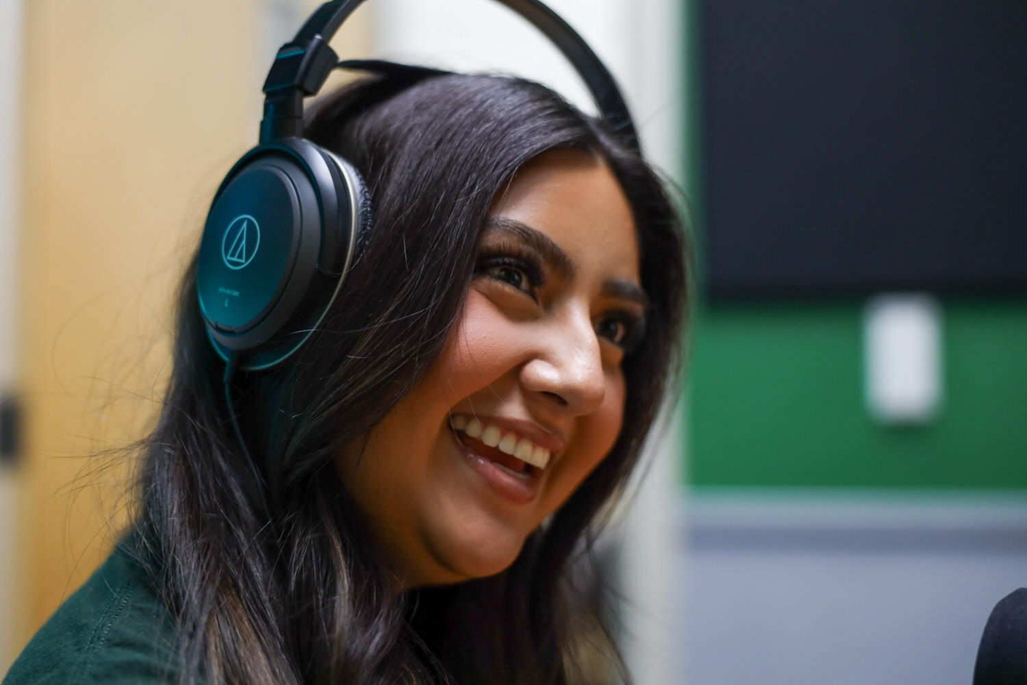 Smiling student wearing headphones in recording setting at a WCC media studio